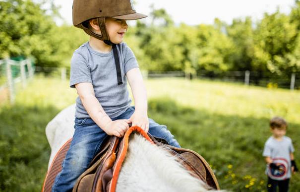 dziecko w kasku siedzące na koniu